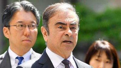 In this May 23, 2019, file photo former Nissan chairman Carlos Ghosn, center, arrives at Tokyo District Court for a pre-trial meeting in Tokyo. Nissan has agreed to pay $15 million and its former chairman Carlos Ghosn is paying $1 million to settle federal regulators' civil fraud charges of hiding from investors more than $140 million in compensation and retirement benefits for Ghosn.