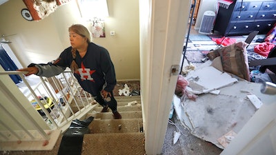 Maria Hernandez climbs her stairwell as she and her family worked to move their belongings out as they sifted through their damaged home in the Bridgeland Lane area of Houston, Sunday, Jan. 26, 2020, after the Watson Grinding Manufacturing explosion early Friday morning. Her ceiling, right, collapsed even further after overnight rains.