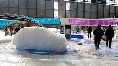 Workers dismantle a booth after that the 90th Geneva International Motor Show (GIMS) is cancelled by Swiss authorities, at the Palexpo in Geneva, Switzerland, Friday, Feb. 28, 2020. The 90th edition of the International Motor Show, scheduled to begin on March 5th, is cancelled due to the advancement of the (Covid-19) coronavirus in Switzerland. The Swiss confederation announced today that all events involving more than 1,000 people would be banned until 15 March.