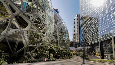 The light reflects off the glass facade of a building on the Amazon campus outside the company headquarter on March 20, 2020, in Seattle.