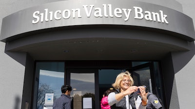 A woman who was part of a line entering the Silicon Valley Bank's headquarters pauses for a selfie in Santa Clara, Calif., on Monday, March 13, 2023.