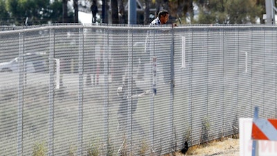 A man is detained by Border Patrol officials as he tries to climb a fence after breaching border fencing separating San Diego from Tijuana, Mexico, Tuesday, Sept. 26, 2017, in San Diego. The man, who said he was from Chiapas, Mexico, was detained by agents as they prepared for a news conference to announce that contractors have begun building eight prototypes of President Donald Trump's proposed border wall with Mexico.