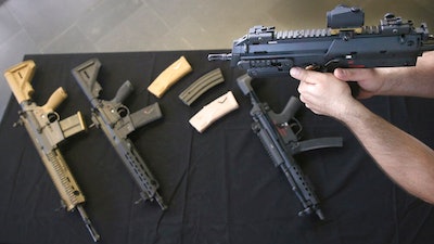 In this Feb. 20, 2019 photo a man holds a weapon of the gun maker Heckler & Koch in Berlin, Germany. The regional court in the German city of Stuttgart has convicted two former employees of gun maker Heckler & Koch over their role in delivering weapons that ended up in troubled areas of Mexico. It has fined the company 3.7 million euros ($4.2 million), the value of the proceeds.