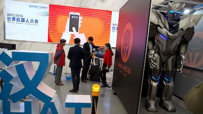 A group of visitors stand near a giant robot standing behind a partition at the World Robot Conference in Beijing.