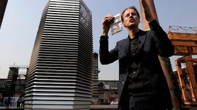 Dutch artist Daan Roosegaarde holds a packet containing smog particles collected by the Smog Free Tower as he presents his machine at D-751art district in Beijing, Thursday, Sept. 29, 2016. In a city where smog routinely blankets the streets and chokes off clean air, a Dutch artist has offered an eccentric solution: a 20-foot metal tower that takes in smog and purifies it like a giant outdoor vacuum cleaner.