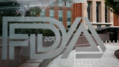 This Thursday, Aug. 2, 2018, file photo shows the U.S. Food and Drug Administration building behind FDA logos at a bus stop on the agency's campus in Silver Spring, Md. The Food and Drug Administration’s first broad testing of food for a worrisome class of nonstick, stain-resistant industrial compounds found high levels in some grocery store meats and seafood and in off-the-shelf chocolate cake, according to unreleased findings FDA researchers presented at a scientific conference in Europe.