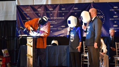 This photo provided by the US Navy shows Stephen Corr welding the outline of Dana Richardson’s initials on the Oregon keel as Dana and Electric Boat President Jeff Geiger look on Saturday July 8, 2017, in North Kingstown, R.I.